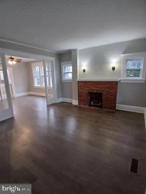 an empty room with wooden floor fire place and windows