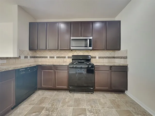 a kitchen with stainless steel appliances granite countertop a stove a sink and a microwave