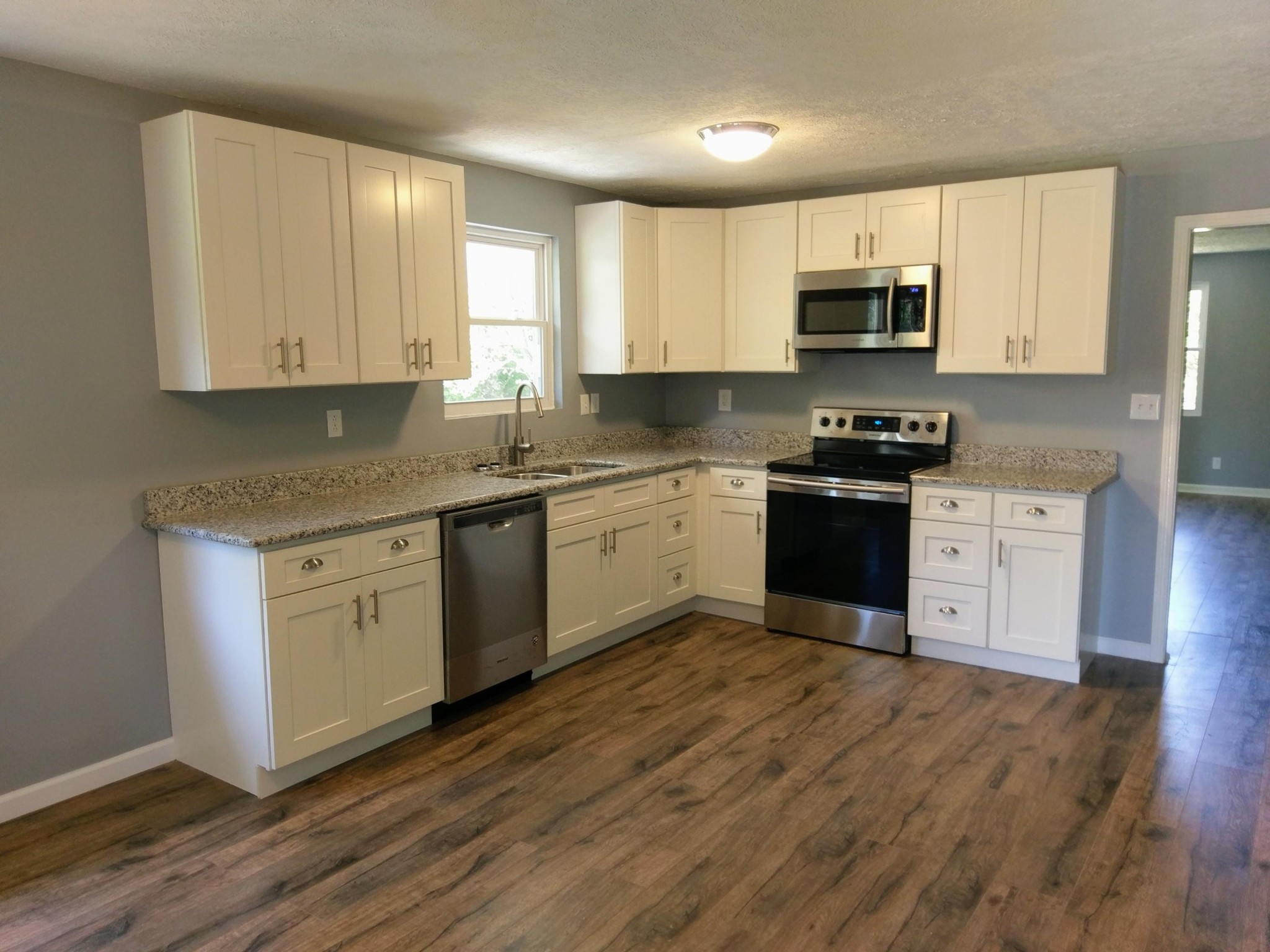 304 Cade Road Ten Mile, TN 37880 - Photo 5 of 19 a kitchen with stainless steel appliances granite countertop white cabinets a sink a stove a refrigerator and microwave with wooden floors