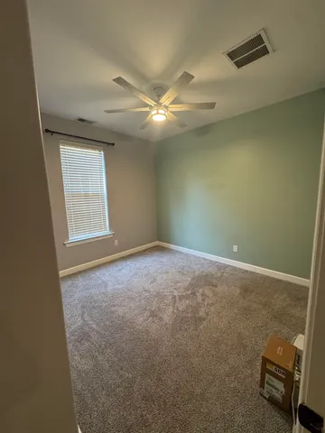an empty room with windows and fan
