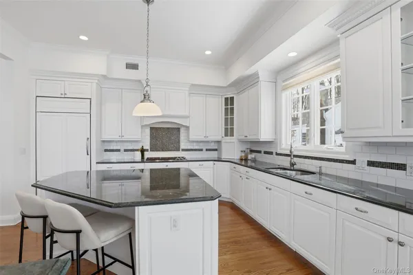 a kitchen with granite countertop a sink and white cabinets