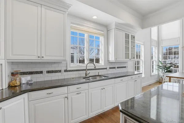 a kitchen with granite countertop white cabinets and sink