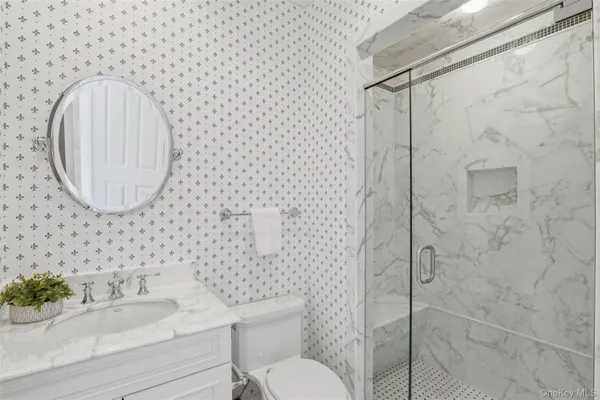 a bathroom with a granite countertop toilet sink and mirror