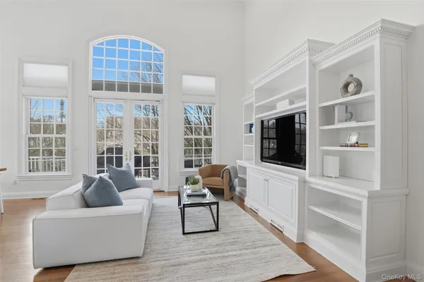 a living room with furniture a flat screen tv and a floor to ceiling window