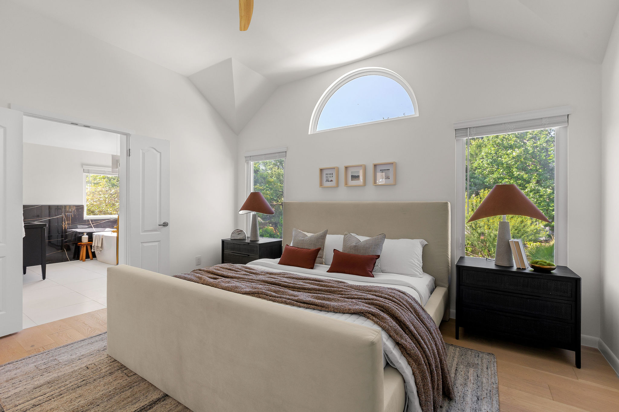 6500 Clay Allison Pass Austin, TX 78749 - Photo 22 of 39 Vaulted ceiling bedroom with light wood-finish flooring, featuring an arched accent window and two rectangular windows with exterior landscape