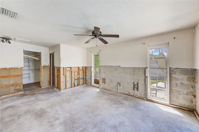 a view of empty room with floor to ceiling window and ceiling fan