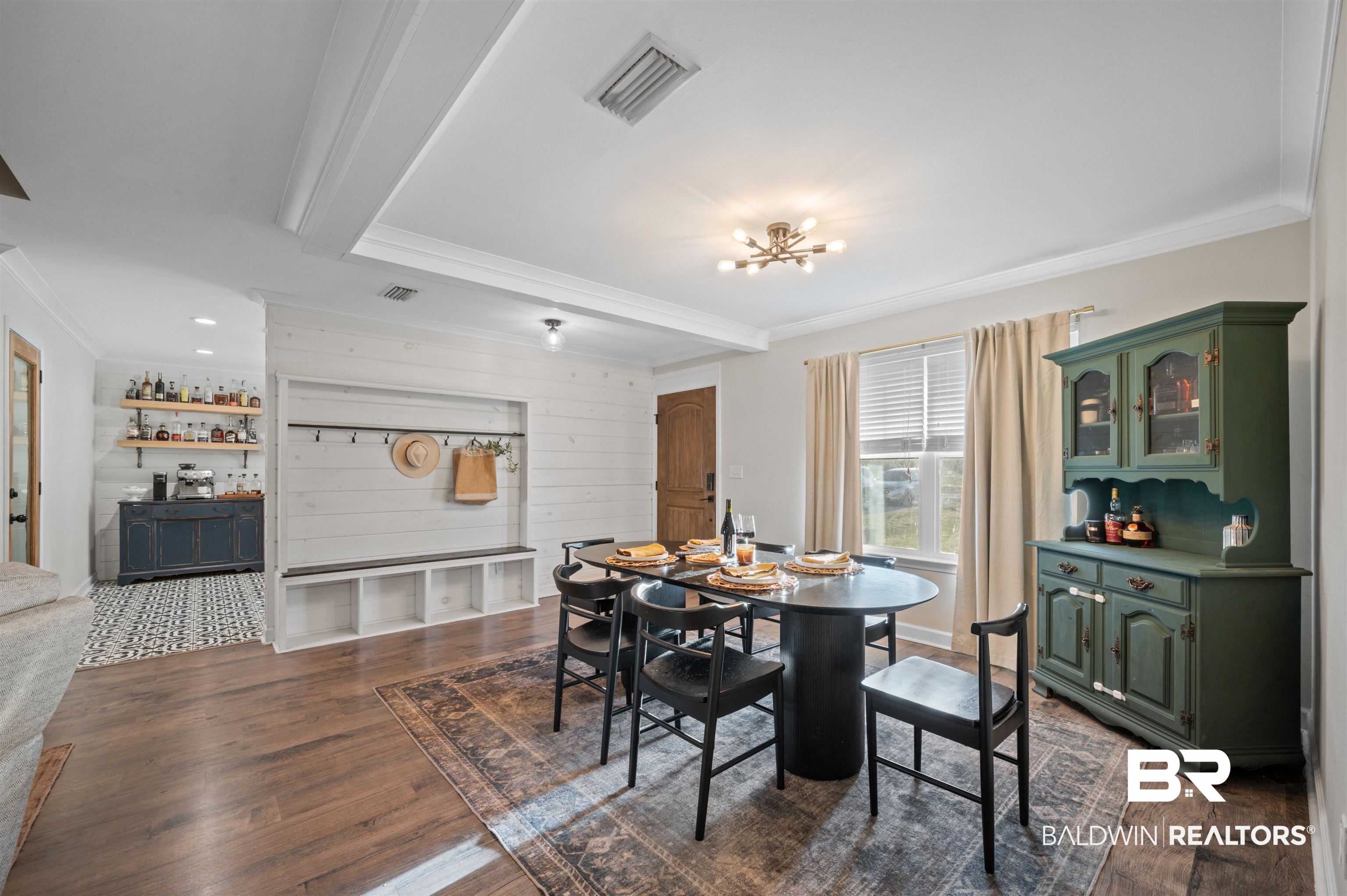 Dining area with visible vents, a bar, ornamental molding, dark wood finished floors, and a notable chandelier