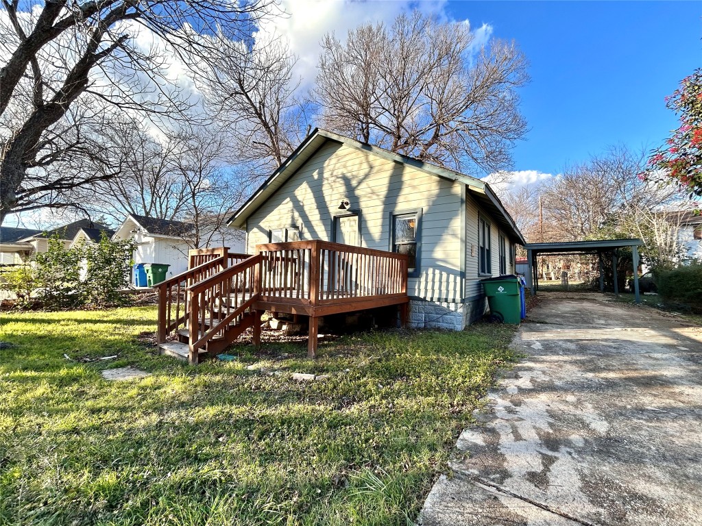 View of front of property featuring a wooden deck, a front yard, driveway, and a carport
