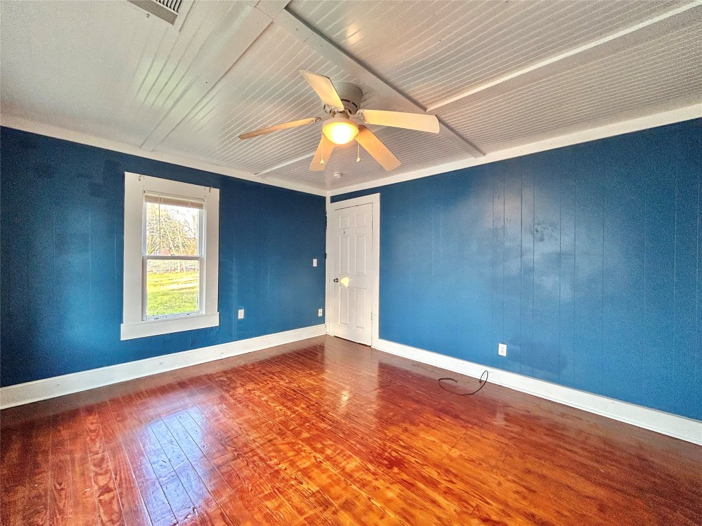 1112 West 3rd Street Taylor, TX 76574 - Photo 18 of 24 Unfurnished room with dark wood-type flooring, ceiling fan, and wood walls