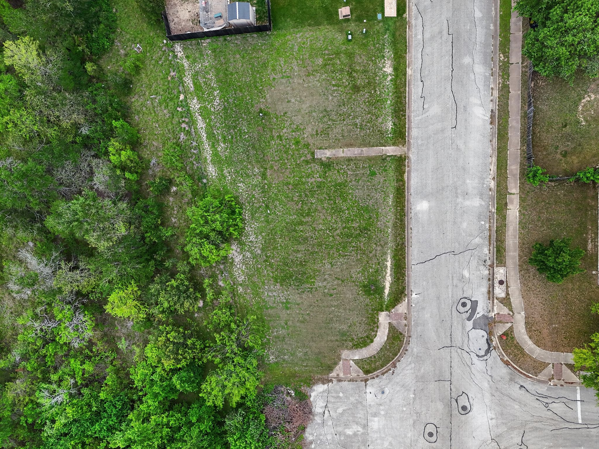 The property features a substantial grassy lot with surrounding trees