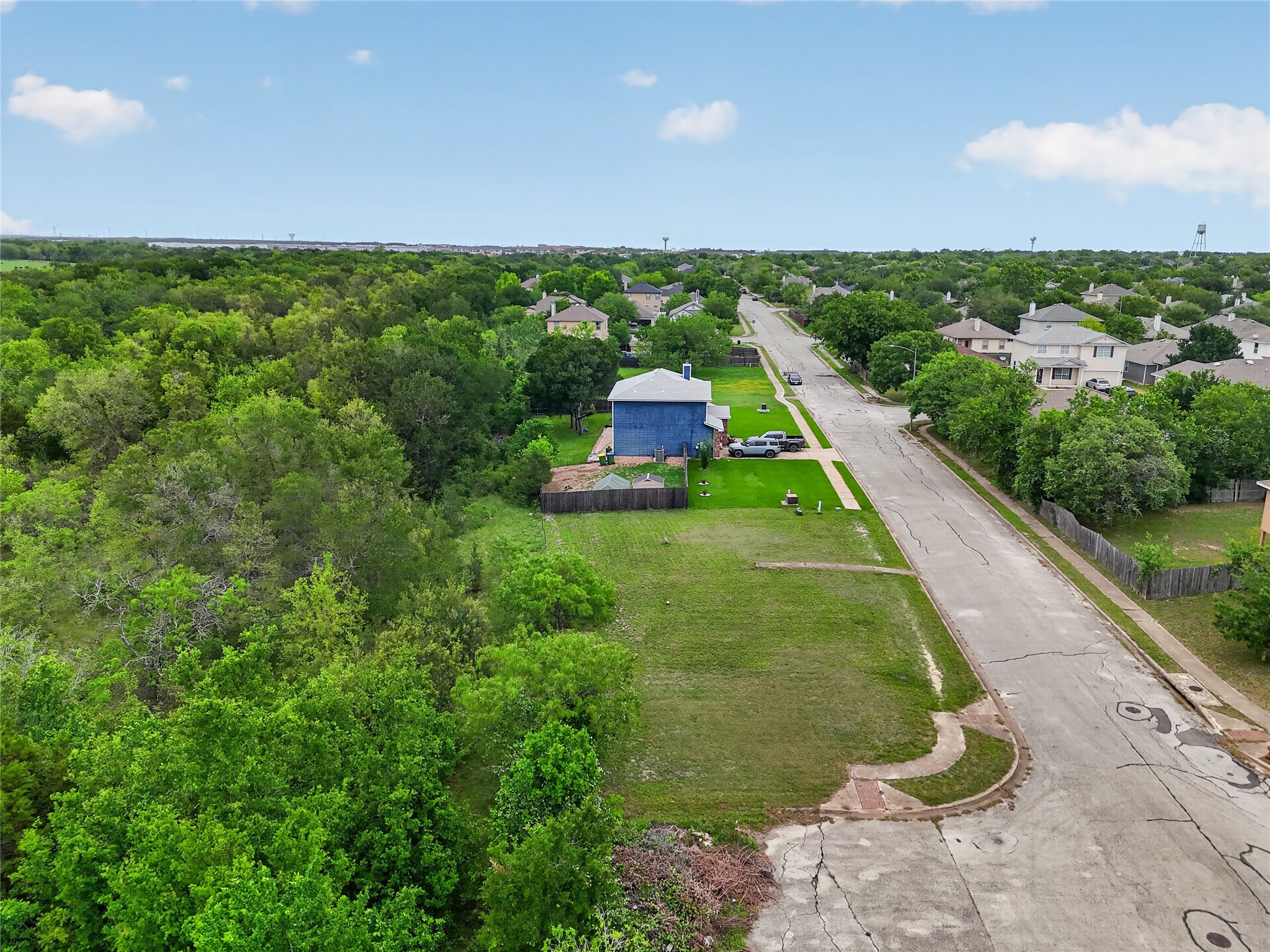 11908 Athens Street Manor, TX 78653 - Photo 12 of 15 Expansive lot featuring a vibrant green lawn and a natural wooded perimeter, located on a paved street