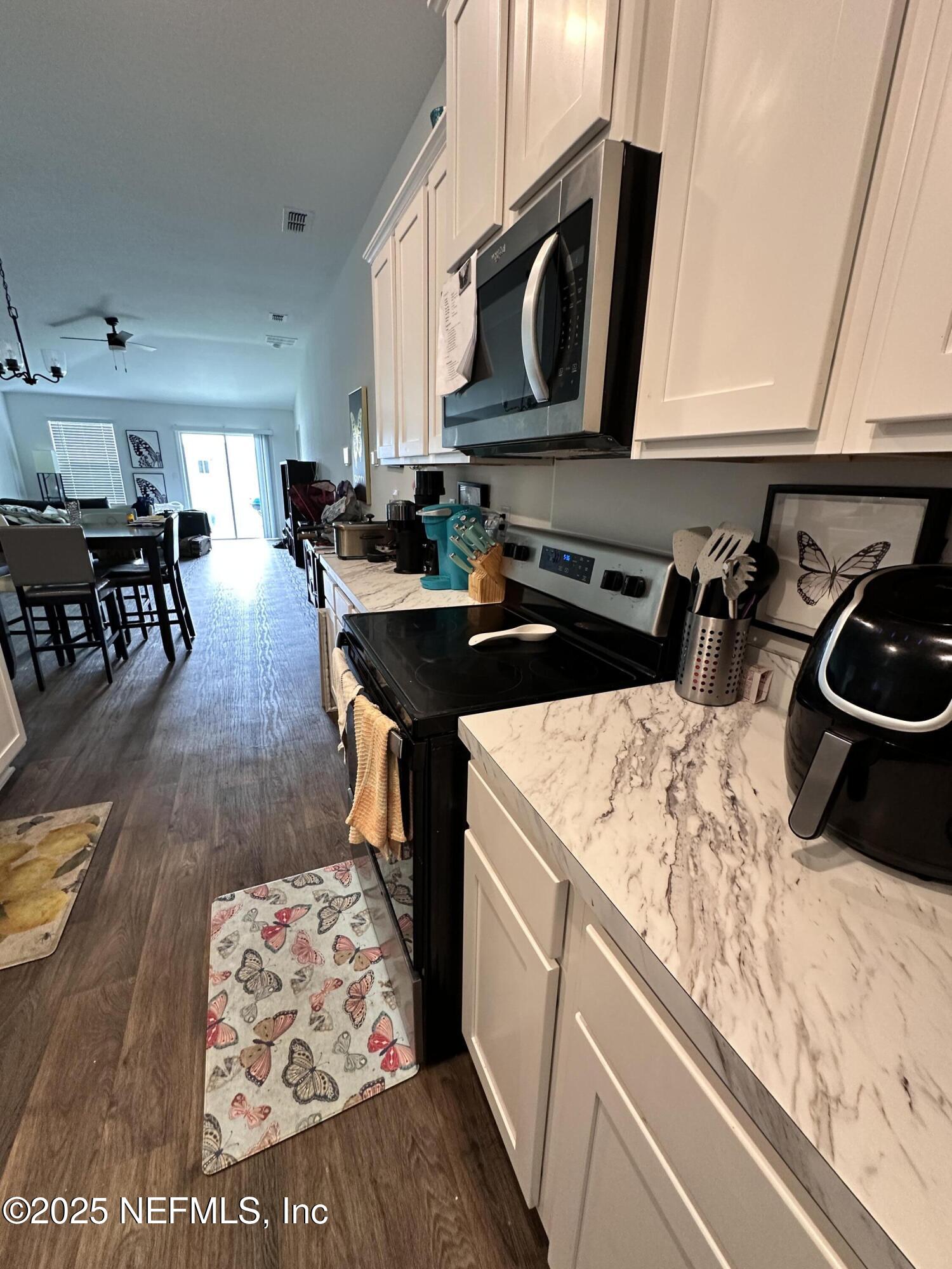2769 Oak Strm Drive Green Cove Springs, FL 32043 - Photo 7 of 17 a kitchen with stainless steel appliances kitchen island granite countertop a stove a sink and a microwave
