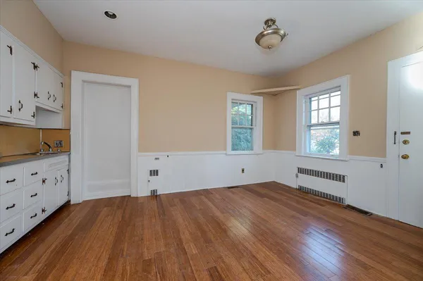 a view of an empty room with window and wooden floor