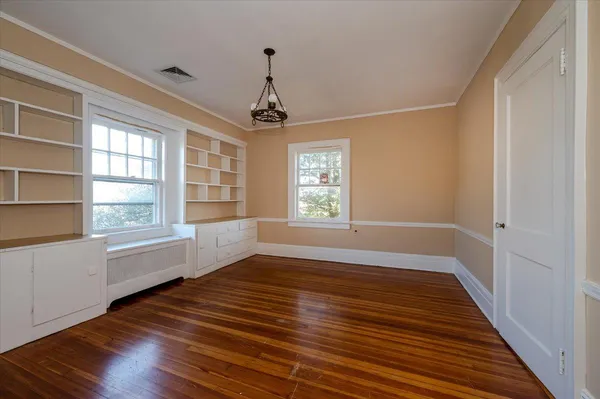 a view of an empty room with a window and wooden floor