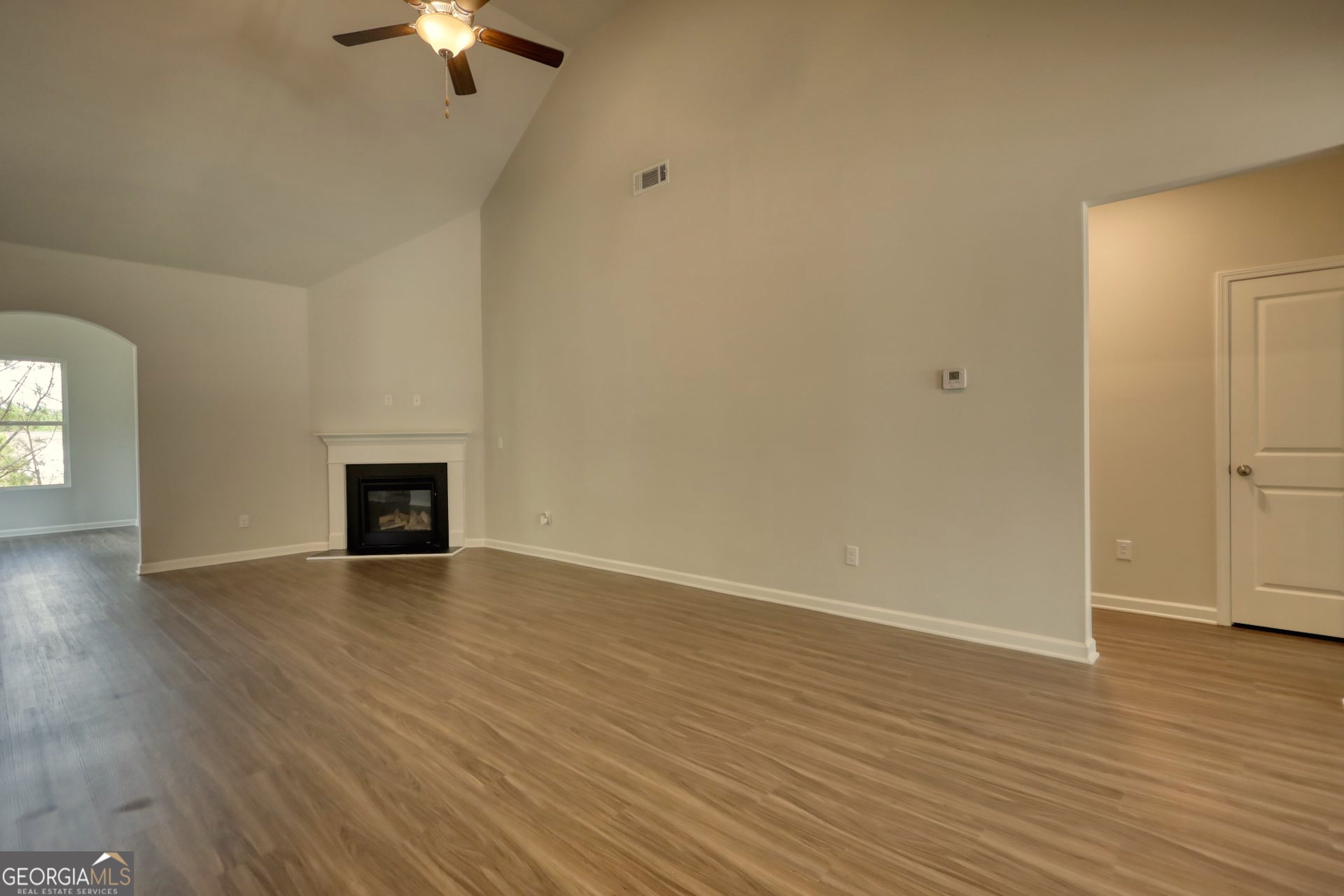 815 Crossroads Court Social Circle, GA 30025 - Photo 3 of 3 an empty room with wooden floor fireplace and windows