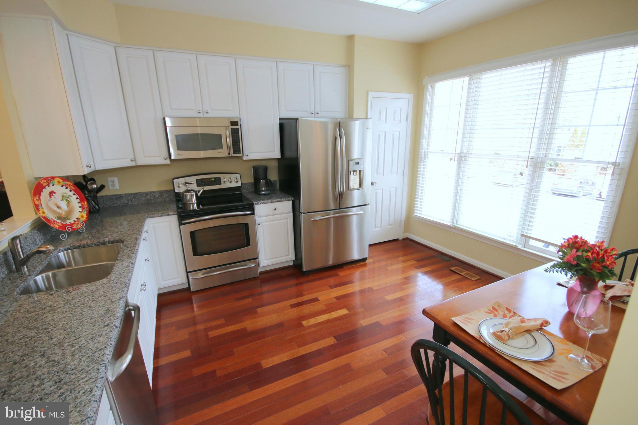 1246 Weatherstone Court Reston, VA 20194 - Photo 3 of 26 a kitchen with stainless steel appliances wooden floors and wooden cabinets