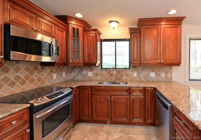 a kitchen with stainless steel appliances granite countertop a stove a sink and a microwave