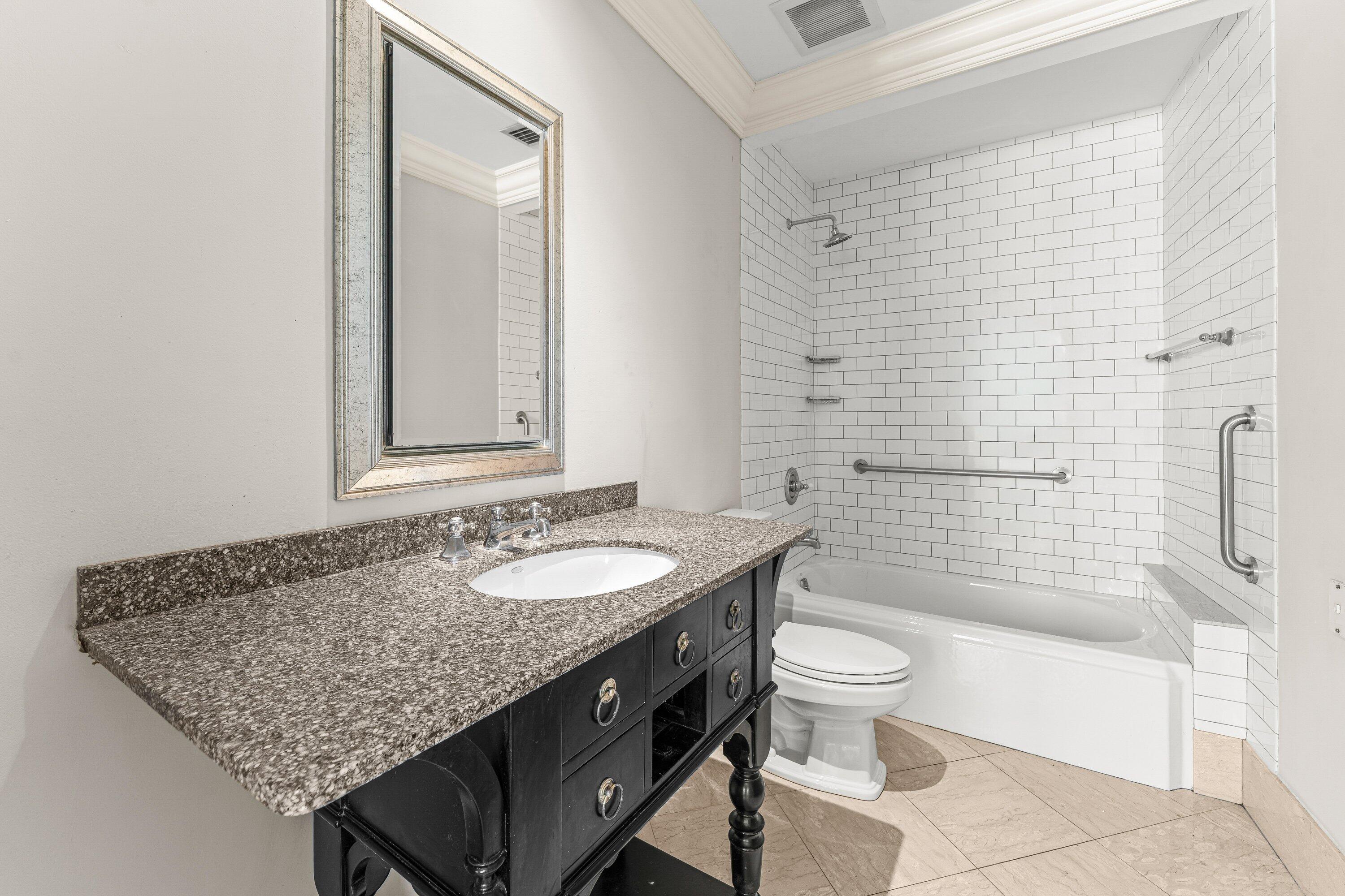 1200 South Flagler Drive, Unit 101 West Palm Beach, FL 33401 - Photo 14 of 44 a bathroom with a granite countertop sink a toilet a mirror and shower