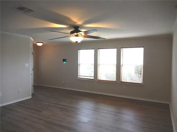 an empty room with wooden floor fan and windows