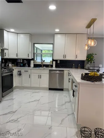 a kitchen with granite countertop a sink a stove top oven and white cabinets