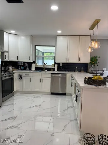 a kitchen with granite countertop a sink a stove top oven and white cabinets