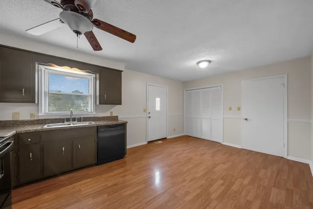 a large kitchen with stainless steel appliances granite countertop a sink and dishwasher a stove with wooden floor