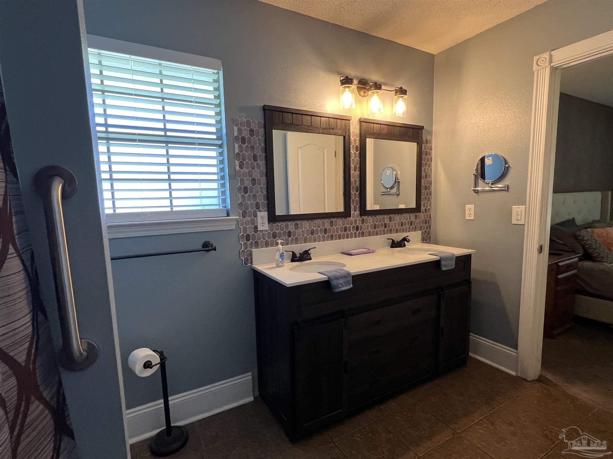 12465 Red Cloud Road Pensacola, FL 32507 - Photo 42 of 68 a bathroom with a double vanity sink a mirror and a bathtub