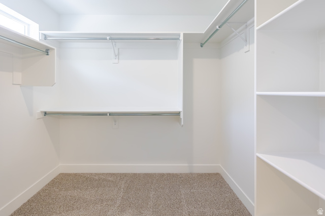 195 West Harmony Rdg Parkway, Unit 601 Mapleton, UT 84664 - Photo 16 of 23 Walk-in closet featuring built-in shelving, multiple hanging rods, a high-set window, and neutral carpeting