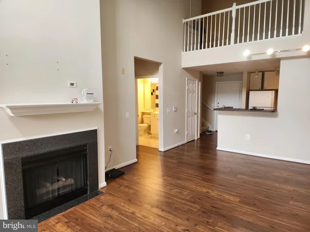 a view of a livingroom with wooden floor and a kitchen