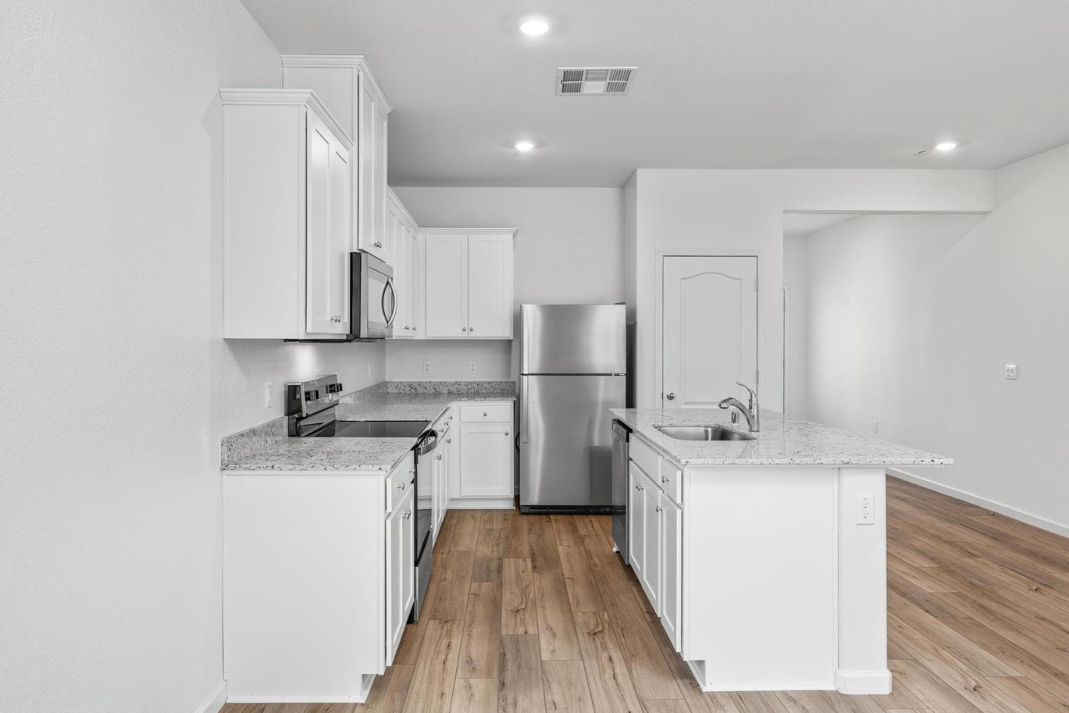 6691 Snedigar Road Riverbank, CA 95367 - Photo 6 of 12 a kitchen with a sink a refrigerator and wooden cabinets