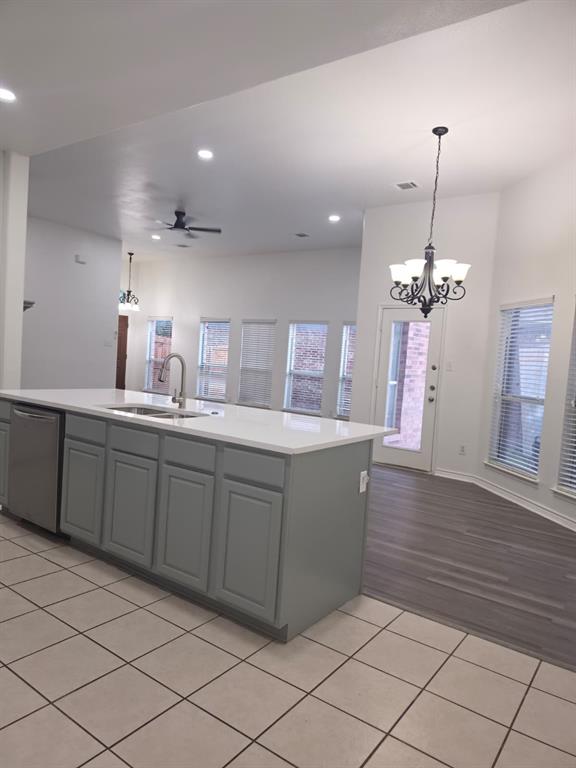 8047 New Kent Road Frisco, TX 75035 - Photo 2 of 27 Kitchen island with light gray cabinetry, a stainless steel dishwasher, and a white countertop with an undermount sink