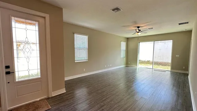 a view of an empty room with a window and wooden floor