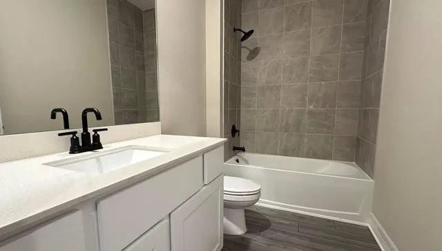 a bathroom with a granite countertop sink a toilet and bathtub