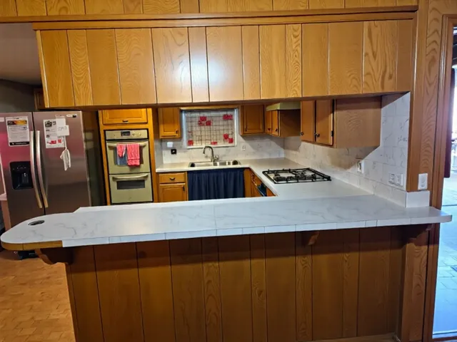 a kitchen with stainless steel appliances a refrigerator a sink a stove top oven