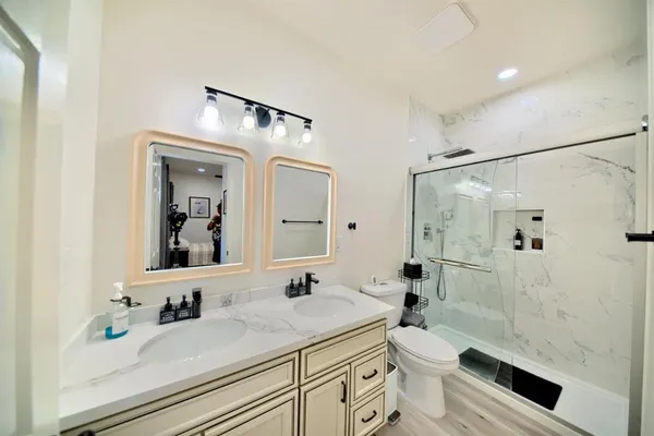 a bathroom with a sink a toilet and shower a mirror