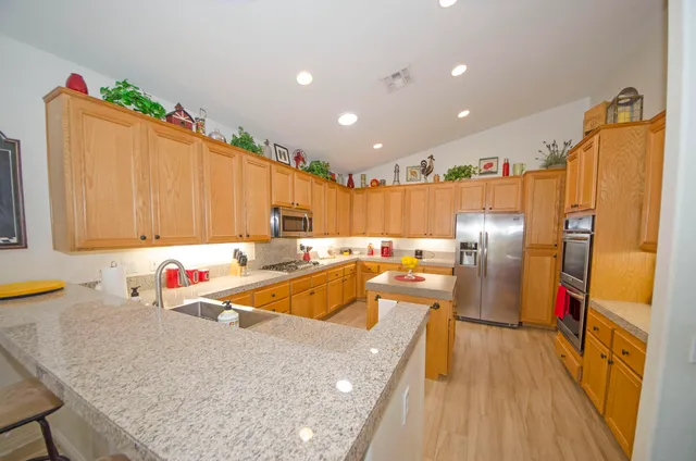 a kitchen with stainless steel appliances granite countertop a sink refrigerator and cabinets