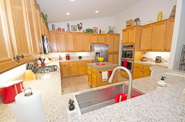 a kitchen with kitchen island granite countertop a sink and a refrigerator