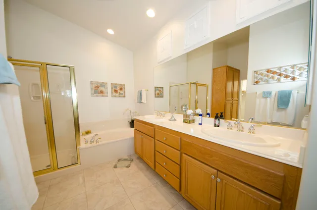 a spacious bathroom with a double vanity sink a mirror and a shower