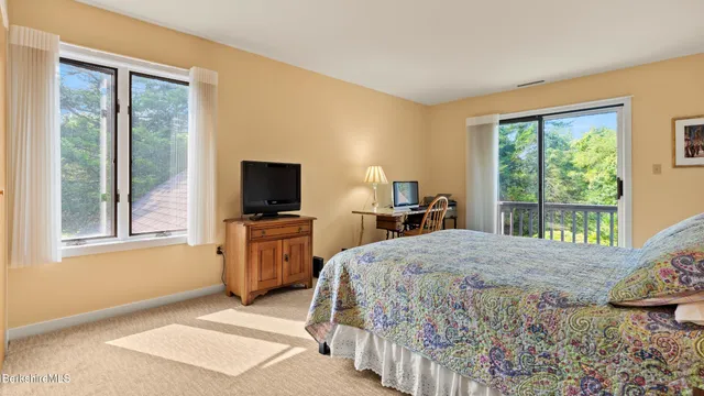 a bedroom with a bed and large windows