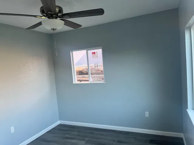 an empty room with a window and a fan