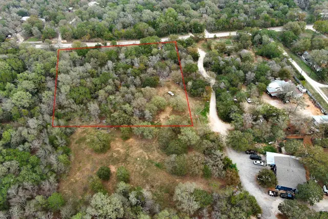 an aerial view of residential houses with outdoor space and trees