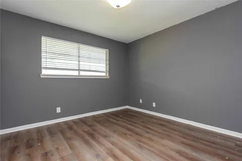 an empty room with wooden floor closet and windows
