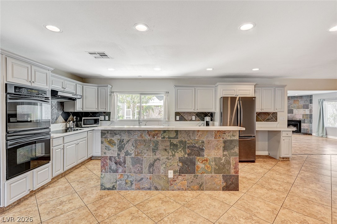 4153 Woodcrest Road Las Vegas, NV 89121 - Photo 11 of 58 A well-appointed kitchen showcasing contemporary appliances and a charming stone island, perfect for culinary endeavors.