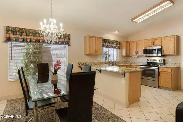 a kitchen with stainless steel appliances granite countertop a stove top oven a sink dishwasher a dining table and chairs with wooden floor