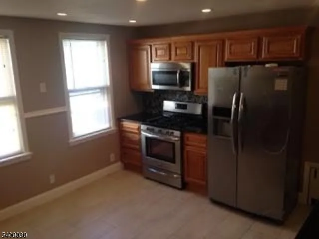 a kitchen with stainless steel appliances granite countertop a refrigerator a stove a sink and a window