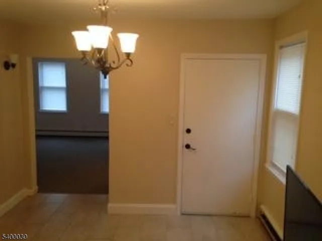 a view of a hallway with wooden floor and chandelier