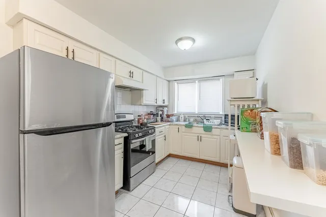 a kitchen with a refrigerator a stove top oven and white cabinets