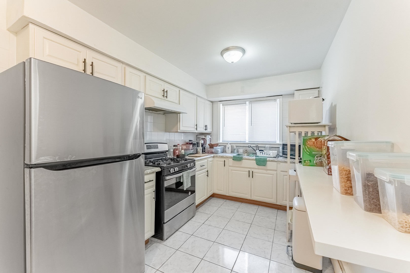 1630 West Chase Avenue, Unit 1N Chicago, IL 60626 - Photo 9 of 11 a kitchen with a refrigerator a stove top oven and white cabinets