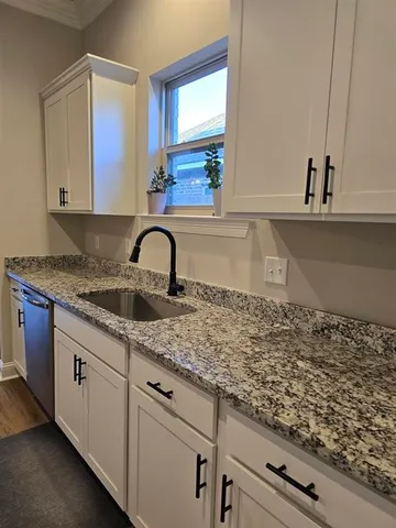 a kitchen with granite countertop white cabinets and sink