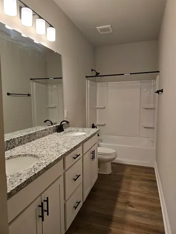 a bathroom with a granite countertop sink a toilet and shower